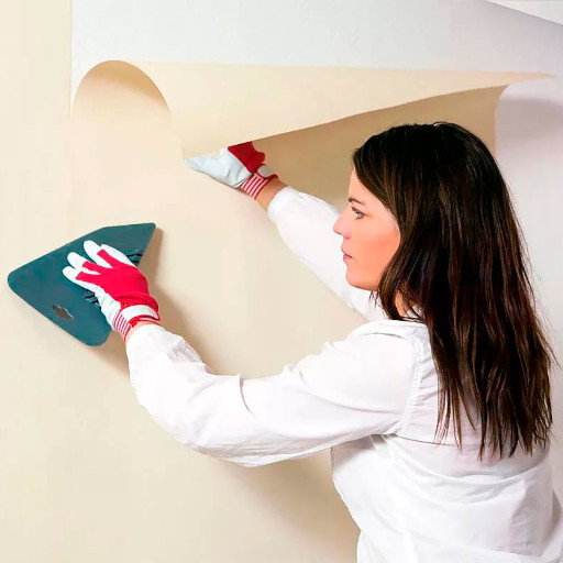 На фото мастер по поклейке обоев в Черкассах. Мастер клеит обои, держа специальное приспособление.